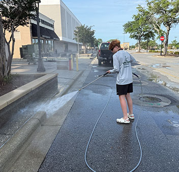 Leprechaun Pro Wash crew pressure washing commercial sidewalks at a Pensacola shopping center