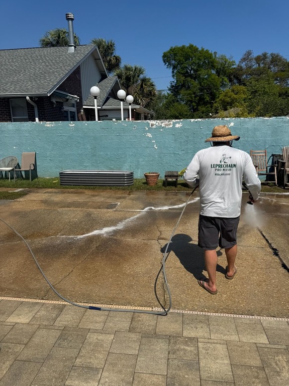 Leprechaun Pro Wash technician soft-washing a concrete pool deck in Gulf Breeze Florida